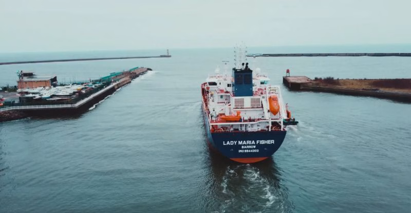 Lady Maria Fisher vessel navigating through port waters with industrial infrastructure visible along the shoreline